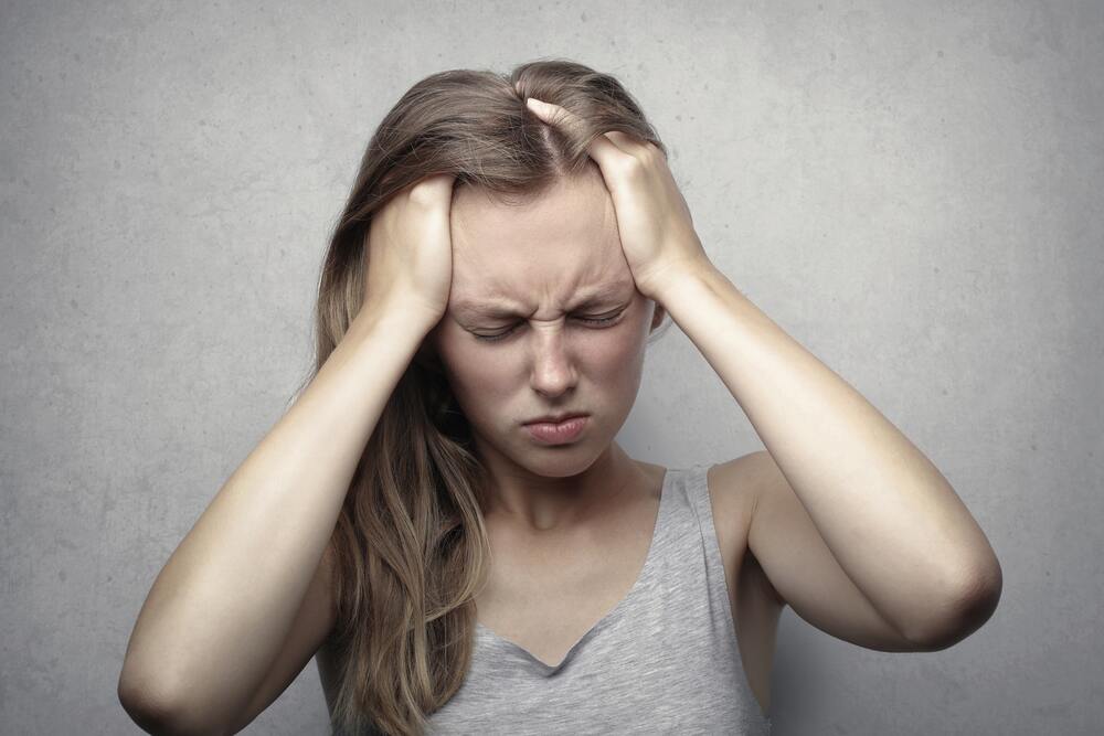 Woman holding her head, migraine, headache, stress headache, aura